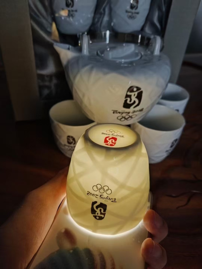 北京2008年奥运特许纪念品 白瓷茶具套装绝版正品 全套一壶五杯， 整体为鸟巢造型，其瓷质细腻、通透如玉、做工精良、外形雅致，凹凸手感舒适，不锈钢把手厚实，茶具银灰色双面LOGO， 收藏价值更高！ 350套， 库存处理！